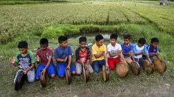 Sejumlah anak laki-laki memainkan rebana tradisional saat mengambil bagian dalam tari Rapa'i Geleng di sepanjang sawah di desa ekowisata Nusa, Lhoknga, Provinsi Aceh, 26 September 2021. Rapa'i Geleng dikembangkan oleh seorang anonim. (CHAIDEER MAHYUDDIN/AFP)