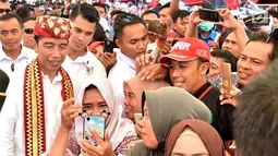 Warga berselfie dengan Presiden Joko Widodo saat acara penyerahan 1.300 sertifikat hak atas tanah untuk masyarakat di Kab Lampung Tengah, Jumat (23/11). Penyerahan sertifikat ini rangkaian kunjungan kerja Presiden ke Lampung. (Liputan6.com/HO/Biropers)