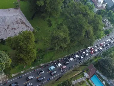 Foto udara memperlihatkan kendaraan wisatawan di Jalan Raya Puncak, Cisarua, Kabupaten Bogor, Jawa Barat, Kamis (5/5/2022). Kapolres Bogor AKBP Iman Imanuddin mengatakan kepadatan arus kendaraan dari arah Jakarta atau Bogor dan juga dari arah Cianjur ke kawasan Puncak masih akan terjadi hingga akhir pekan nanti. (Liputan6.com/Herman Zakharia)