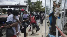 Para Migran Haiti berjalan menaiki perahu di Necocli, Kolombia, Rabu (28/7/2021). Ribuan migran terdampar di kota pelabuhan Kolombia saat mereka menunggu kapal menyeberang ke negara tetangga Panama dalam perjalanan mereka ke Amerika Serikat. (AP Photo/Ivan Valencia)