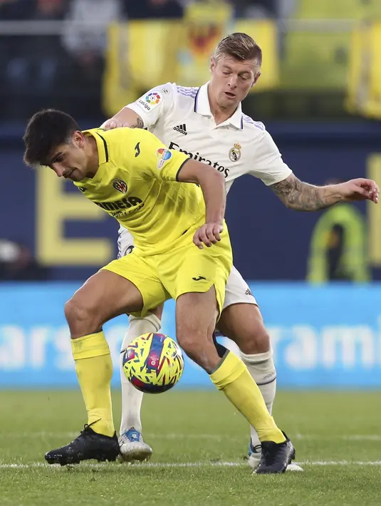 <p>Gelandang Real Madrid, Toni Kroos berusaha merebut bola dari gelandang Villarreal, Gerard Moreno selama pertandingan lanjutan La Liga Spanyol di Estadio De La Ceramica di Villareal, Spanyol, Sabtu (7/1/2023). Kemenangan ini mengantar Villarreal naik ke peringkat lima usai mengoleksi 27 poin. (AP Photo/Alberto Saiz)</p>