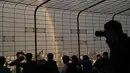 Orang-orang mengambil foto pelangi ganda melalui pagar di Central Television Tower di Beijing (26/8/2021). Keindahan pelangi ganda dimanfaatkan warga Beijing untuk diabadikan lewat foto dan berfoto dengan latar pelangi itu. (AFP/Jade Gao)