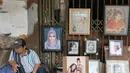 Seorang pelukis menunggu calon pemesan di trotoar Kawasan Glodok, Jakarta, Selasa (15/5). Bagi warga yang ingin dilukis, biasanya harus menyerahkan foto sebagai contoh materi lukisan. (Liputan6.com/Herman Zakharia)