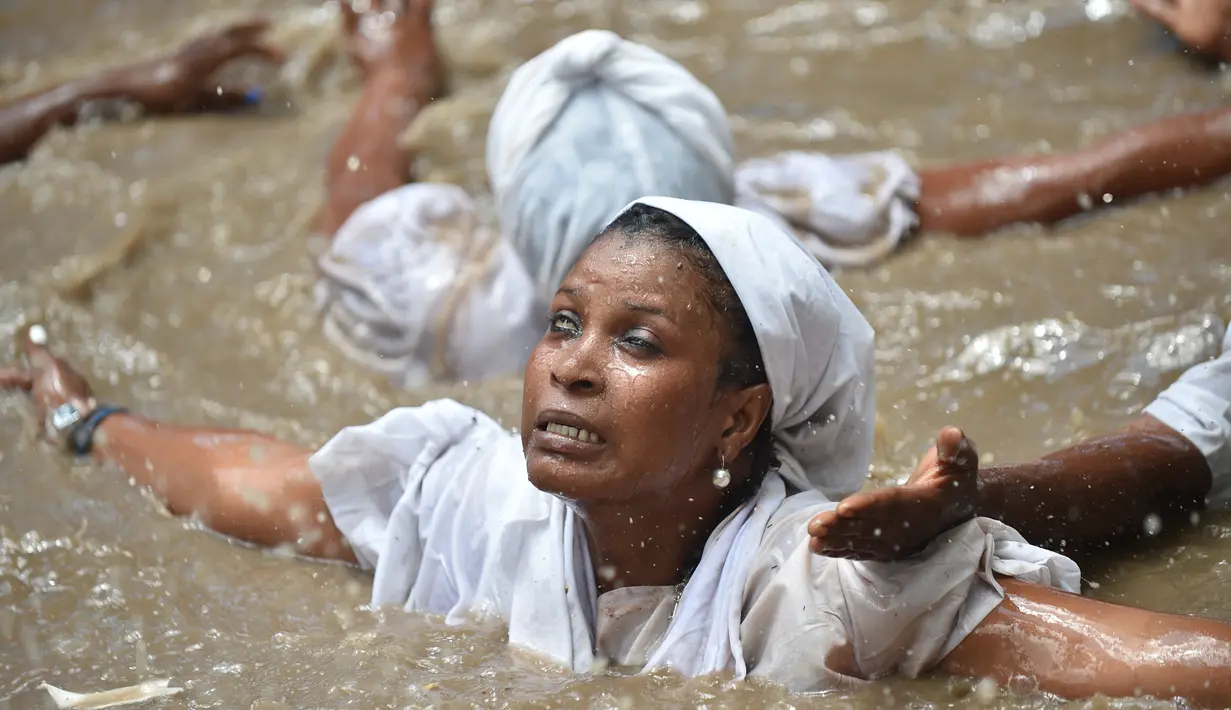 Seorang wanita pengikut Voodoo Haiti mandi di kolam suci selama upacara Voodoo di Souvenance, Haiti (4/1). Sejumlah ritual digelar para pengikuti Voodoo Haiti ini selam akhir pekan perayaan Paskah. (AFP/Hector Retamal)