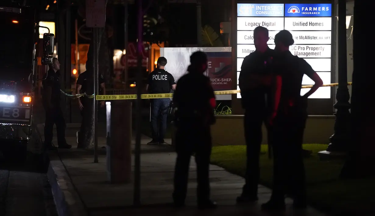 Petugas polisi berdiri di luar gedung bisnis tempat penembakan terjadi di Orange, California California (31/3/2021).  Tersangka ditahan dan juga dibawa ke rumah sakit. (AP Photo/Jae C. Hong)