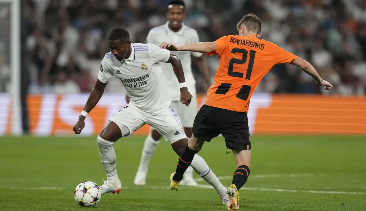 Bek Real Madrid David Alaba berebut bola dengan gelandang Shakhtar Donetsk Artem Bondarenko dalam matchday ketiga Grup F Liga Champions 2022/2023 di Santiago Bernabeu, Kamis dini hari WIB (6/10/2022). Tiga gol Madrid yang tercipta dalam laga ini seluruhnya tercipta di babak pertama. (AP Photo/Bernat Armangue)