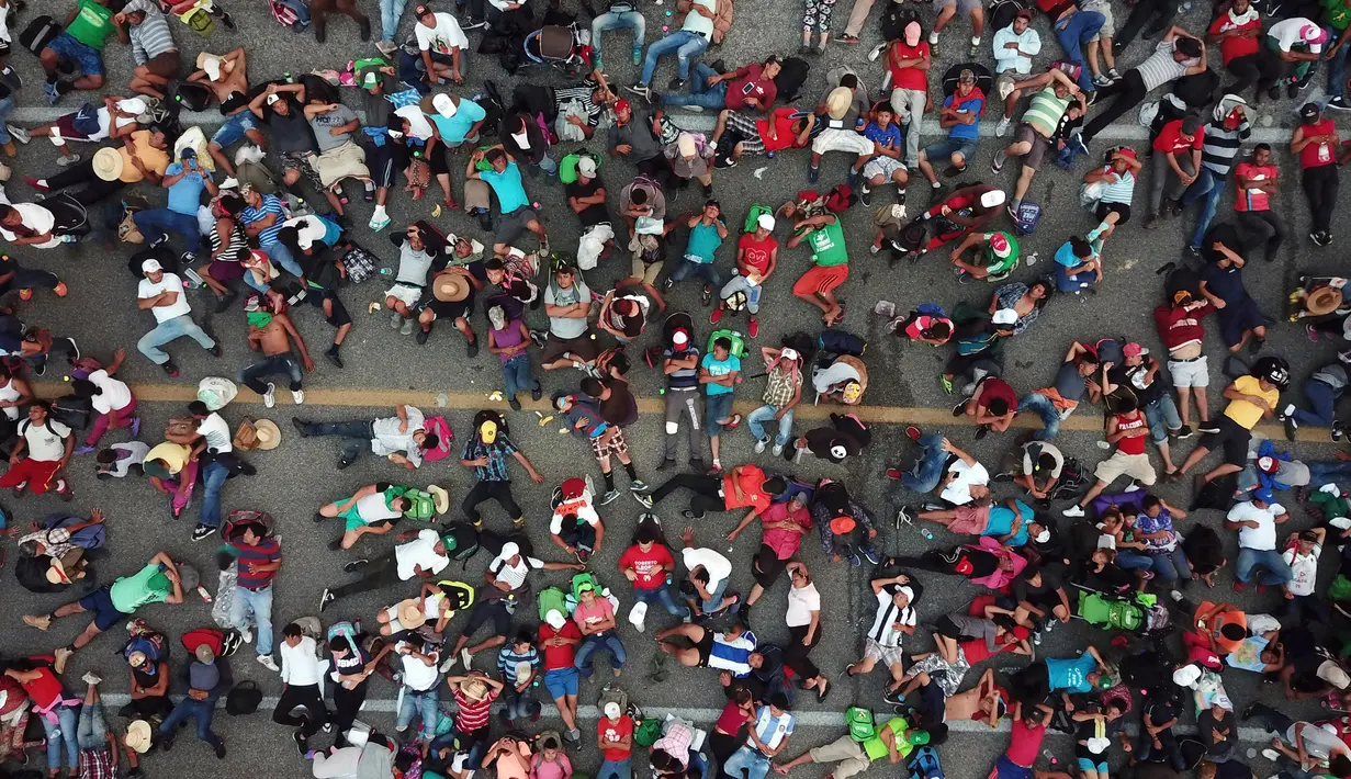 Rombongan imigran Amerika Tengah tujuan Amerika Serikat beristirahat setelah polisi federal menghalangi mereka untuk menyeberangi jembatan antara Chiapas dan Oaxaca di luar Kota Arriaga, Meksiko, Sabtu (27/10). (AP Photo/Rodrigo Abd)
