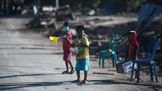 Anak-anak yang terkena dampak gempa meminta sumbangan pada pengguna jalan yang melintas di Donggala, Sulawesi Tengah, Jumat (5/10). Akibat terlambatnya pasokan bantuan, mereka terpaksa meminta sumbangan hingga turun ke jalan. (AFP PHOTO / Jewel SAMAD)