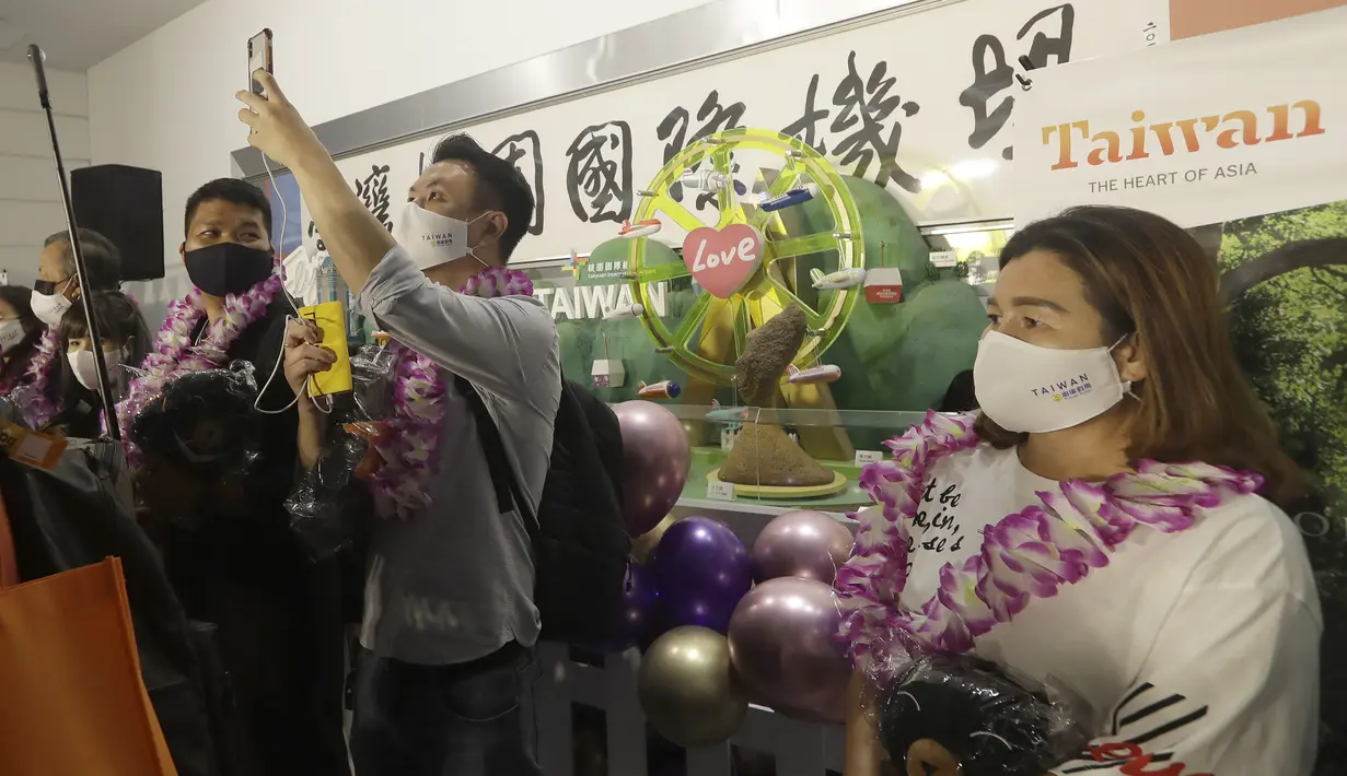 Rombongan pertama wisatawan asing berfoto setelah tiba di Bandara Internasional Taoyuan di Taoyuan, Taiwan Utara, Kamis (13/10/2022). Pemerintah Taiwan memutuskan untuk mulai menuju ke endemisitas setelah populasinya sudah dipastikan melakukan vaksinasi COVID-19 dengan baik. (AP Photo/Chiang Ying-ying)