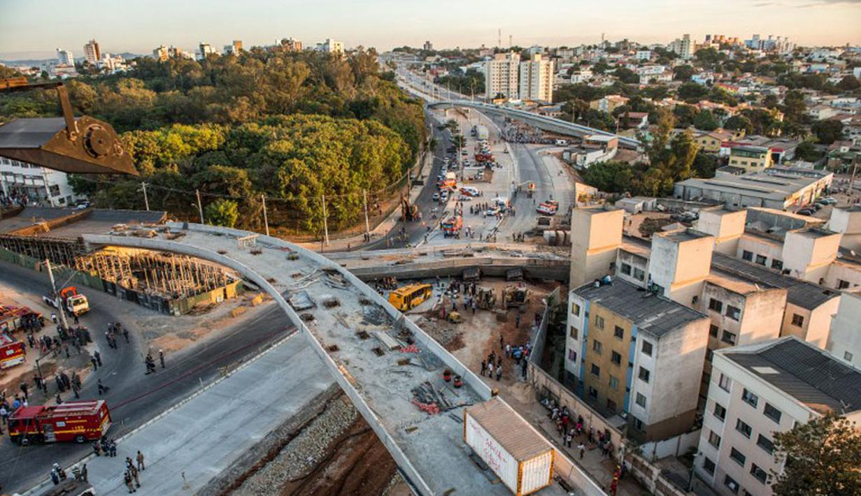 Petugas pemadam kebakaran dan polisi setempat berusaha melakukan evakuasi terhadap kendaraan yang hancur akibat runtuhnya sebuah jembatan layang di Belo Horizonte, Brasil, (3/7/2014). (AFP PHOTO/Pedro Duarte)