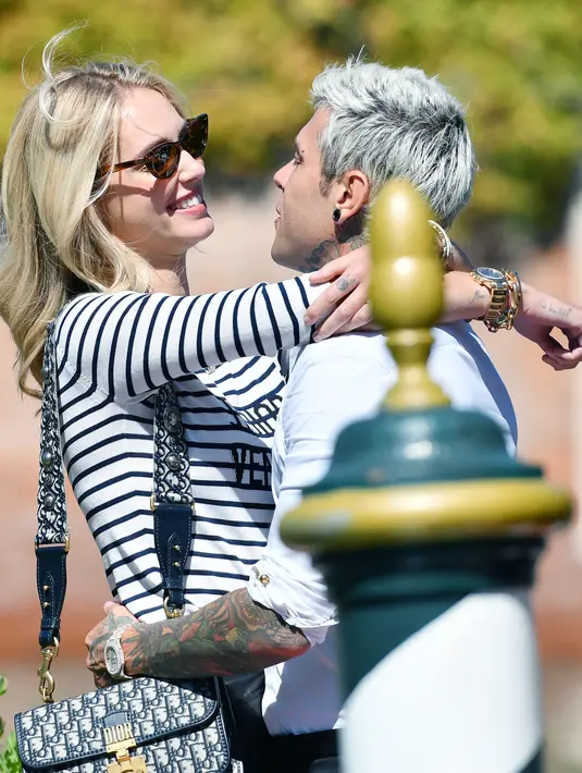 Blogger sekaligus perancang busana Chiara Ferragni (kiri) merangkul dan memandangi suaminya rapper Federico Leonardo Lucia atau Fedez saat tiba untuk menghadiri Venice Film Festival 2019 di Dermaga Hotel Excelsior, Venesia, Italia, Selasa (3/9/2019). (Alberto PIZZOLI/AFP)