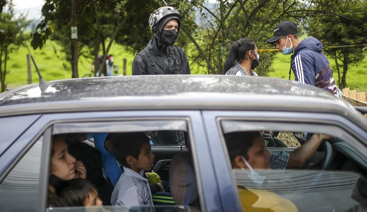 Sebuah keluarga duduk di mobil mereka di sebuah penghalang jalan yang didirikan oleh pengunjuk rasa anti-pemerintah di Madrid, di pinggiran Bogota, Kolombia (28/5/2021). (AP Photo/Ivan Valencia)