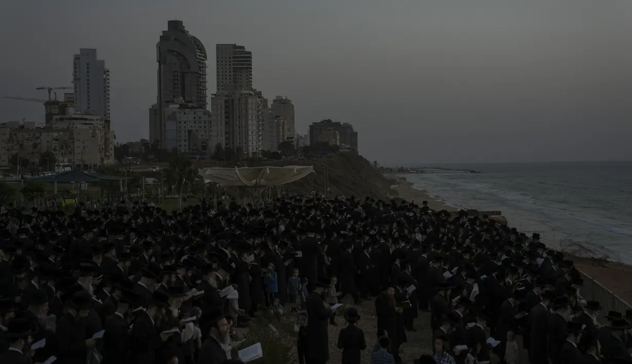 Kaum Yahudi Ultra-Ortodoks mengelilingi kolam plastik dengan air dan ikan saat mereka berpartisipasi dalam upacara Tashlich di kota ultra-Ortodoks Israel Bnei Brak dekat Tel Aviv, Senin, 3 Oktober 2022. Upacara ini dilakukan sehari sebelum perayaan hari raya Yahudi, Yom Kippur, hari paling suci dalam tahun Yahudi yang dimulai pada Selasa. (AP Photo/Oded Balilty)