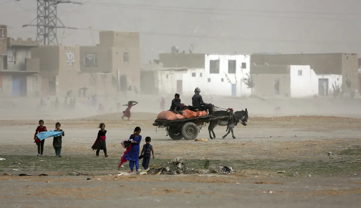 Anak-anak Afghanistan bermain saat badai pasir di pinggiran Kabul, Afghanistan (25/8/2020). Sebuah badai pasir hebat melanda Kabul. Badai menyebabkan jarak pandang jadi berkurang. (AP Photo / Rahmat Gul)