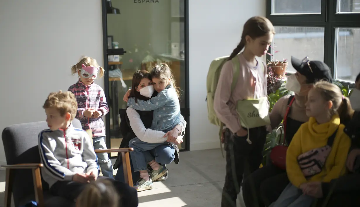 Anak-anak pengungsi dari Ukraina menunggu dengan ibu mereka untuk memulai kelas mereka di Berlin, Jerman, Senin (21/3/2022). Kedua kelas privat pengungsi tersebut disatukan oleh dua relawan Berlin yang berhasil menggalang dana dan mendapatkan ruang kelas gratis. (AP Photo/Markus Schreiber)