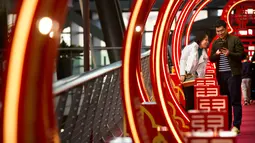 Pengunjung berfoto di sebuah jembatan bertema Imlek di sebuah pusat perbelanjaan kelas atas di Beijing (21/2). Jembatan berwarna merah yang bertema Imlek ini menjadi pusat perhatian dan tempat berfoto pengunjung. (AP Photo / Mark Schiefelbein)