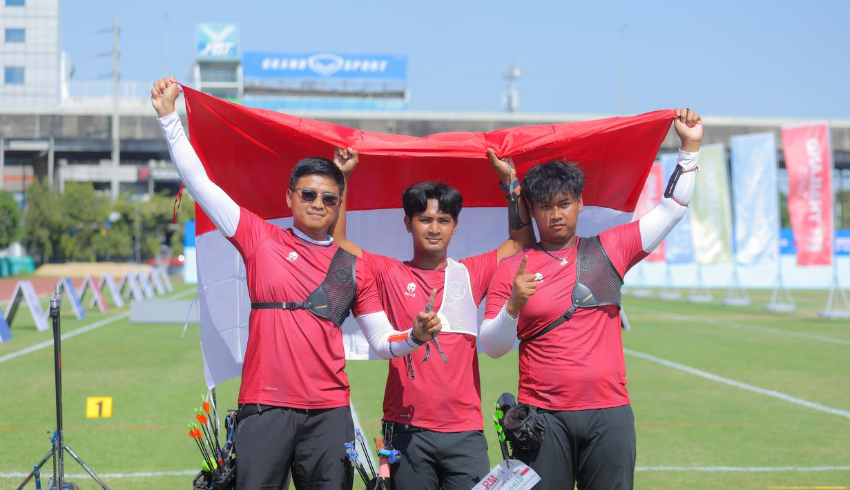 Tim panahan Indonesia, Riau Ega Agata Salsabilla, Ahmad Khoirul Baasith dan Arif Dwi Pangestu (kiri ke kanan) memegang bendera Merah Putih usai memenangi nomor recurve beregu putra SEA Games 2025 di Football Field 1, Bangkok, Thailand, Rabu (17/12/2025). Indonesia kembali menambah koleksi raihan medali emas SEA Games 2025 Thailand. (Bola.com/Bagaskara Lazuardi)