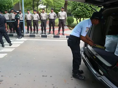 Pamdal DPR mengecek kendaraan sementara sejumlah aparat kepolisian berjaga di pintu masuk Gedung MPR/DPR RI,  Senayan, Jakarta, Jumat (31/3). Polda Metro Jaya memberikan pengamanan ketat di sekitar DPR terkait aksi 31 Maret. (Liputan6.com/Johan Tallo)
