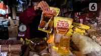 Penjual memperlihatkan minyak goreng kemasan di kiosnya Pasar Kebayoran Lama, Jakarta, Rabu (19/1/2022). Pemerintah resmi mengimplementasikan kebijakan minyak goreng satu harga Rp14.000 per liter untuk semua jenis kemasan mulai hari ini. (Liputan6.com/Johan Tallo)