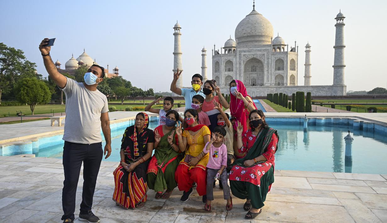 Sekelompok wisatawan berfoto dengan latar belakang Taj Mahal setelah dibuka kembali untuk pengunjung di Agra, Rabu (16/6/2021). Taj Mahal, yang terkenal sebagai ikonik India telah dibuka kembali untuk umum, ketika negara itu mulai melonggarkan pembatasan Covid-19. (Money SHARMA/AFP)