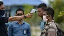 Seorang petugas Urusan Kelautan dan Perikanan Indonesia memeriksa suhu tubuh nelayan Myanmar ketika mereka dideportasi setelah ditahan selama delapan bulan di Banda Aceh (5/8/2020). Mereka ditangkap karena penangkapan ikan ilegal di perairan Aceh sepanjang selat Malaka. (AFP Photo/Chaideer Mahyuddin