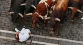 Seorang pengunjung festival terjatuh di depan banteng-banteng aduan Victoriano del Río saat acara lari banteng ketiga di festival San Fermín di Pamplona, Spanyol, Kamis, 9 Juli 2026. (AP Photo/Miguel Oses)