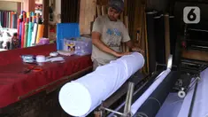 Pedagang menggulung bahan kain yang akan dijual di kawasan Tangerang, Banten, Sabtu (25/9/2021). Program Restrukturisasi Mesin/Peralatan tahun 2021 bertujuan meningkatkan kembali performa industri Tekstil dan Produk Tekstil (TPT) sebagai sektor strategis. (Liputan6.com/Angga Yuniar)