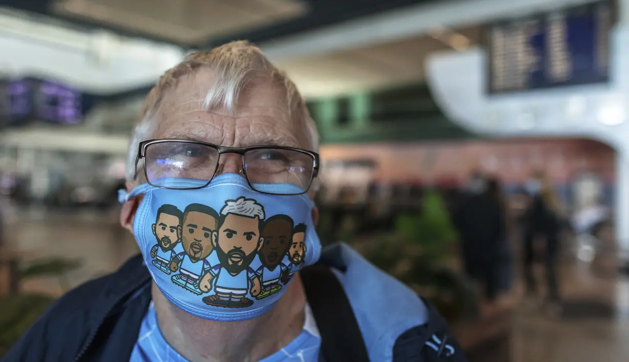 Seorang suporter Manchester City memakai masker wajah bergambar para pemain tim, di bandara di Porto, Portugal (28/5/2021). Klub Inggris Manchester City dan Chelsea akan memainkan final Liga Champions di stadion Dragao di Porto pada Sabtu malam atau Minggu (30/5/2021) dini hari. (AP Photo/Luis Vieir