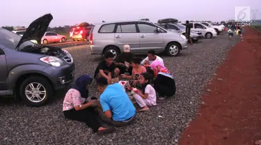 Pemudik menyantap hidangan berbuka puasa di pinggir Tol Fungsional Pemalang-Batang, Jawa Tengah, Minggu (10/6). Sambil berbuka mereka juga mendinginkan kendaraannya. (Liputan6.com/Arya Manggala)