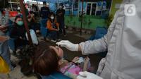 Petugas medis mengambil sampel lendir wisatawan untuk tes usap atau Swab Antigen di Pelabuhan Kali Adem, Jakarta, Kamis (31/12/2020). Pemeriksaan swab antigen wisatawan yang akan libur Tahun Baru di Kepulauan Seribu dilakukan untuk mencegah penyebaran COVID-19. (merdeka.com/Imam Buhori)