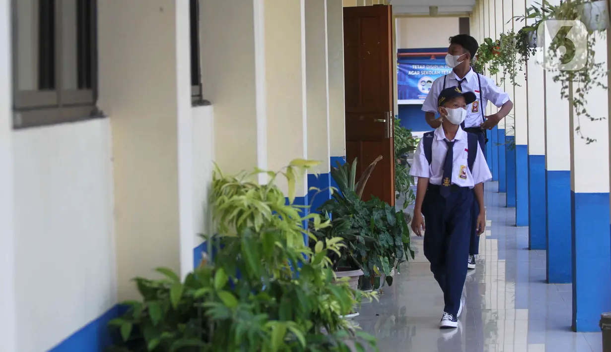 Siswa berjalan di lorong saat akan mengikuti hari pertama pembelajaran tatap muka di SMP 26 Depok, Depok, Jawa Barat, Senin (24/1/2022). Pemerintah Kota Depok mulai menggelar Pembelajaran Tatap Muka (PTM) secara penuh atau 100 persen mulai hari ini. (Liputan6.com/Herman Zakharia)