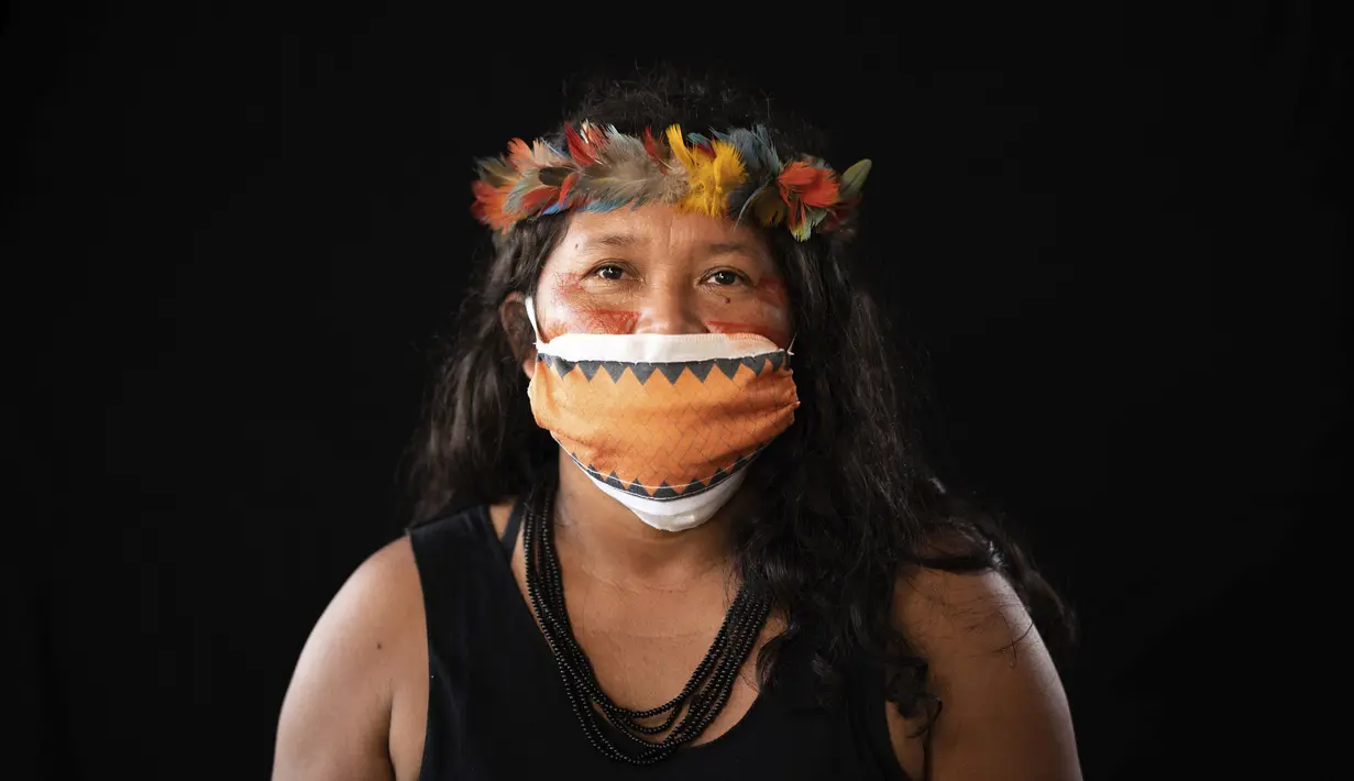 Terezinha de Souza (45) dari kelompok etnis pribumi Sateré Mawé mengenakan pakaian tradisional sukunya dan masker saat pandemi virus corona COVID-19 di daerah Gaviao, dekat Manaus, Brasil, Jumat (29/5/2020). Pada akhir Mei, dia jatuh sakit dengan tanda-tanda terpapar COVID-19. (AP Photo/Felipe Dana)