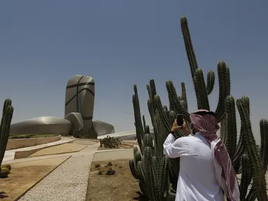 Seorang pria Saudi memfilmkan bagian luar King Abdulaziz Center for World Culture, juga dikenal sebagai Ithra, di Dammam, Arab Saudi, Minggu (27/6/2021).  Pusat tersebut dibangun oleh Saudi Aramco dan diresmikan oleh Raja Salman pada 2016. (AP Photo/Amr Nabil)