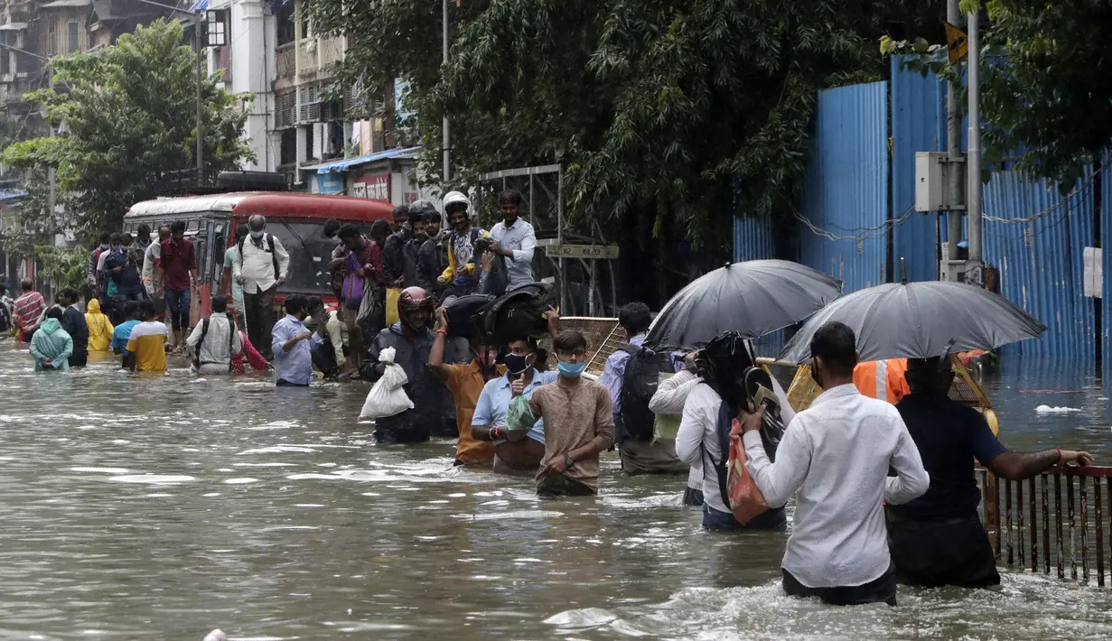 Orang-orang berjalan melewati jalan yang tergenang air setelah hujan lebat di Mumbai, India, Rabu (23/9/2020). Musim hujan di India berlangsung dari Juni hingga September. (AP Photo/Rajanish Kakade)