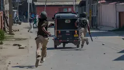 Tentara India berlindung di belakang bajaj saat mengejar warga Kashmir yang memprotes pembunuhan kelompok militan di Srinagar (4/1). Sebelumnya, 12 orang dari kelompok militan tewas saat bentrok dengan pasukan pemerintah India. (AP Photo / Dar Yasin)