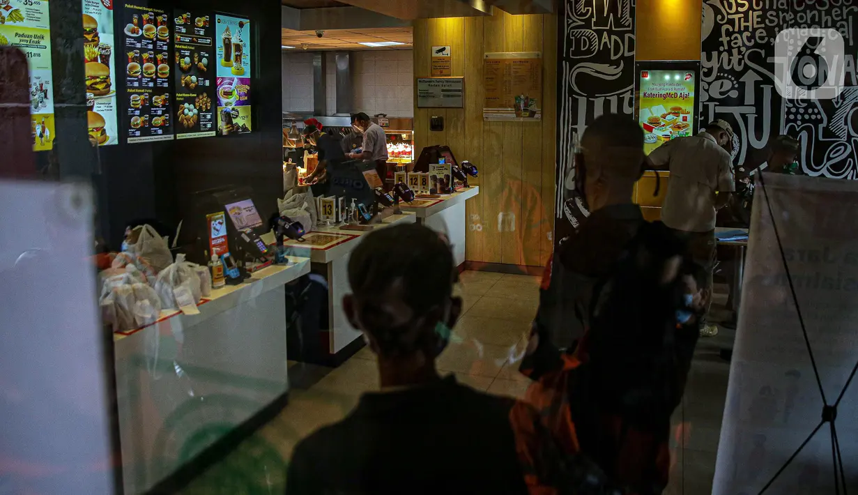 Pegawai menyiapkan pesanan di gerai cepat saji McDonald's Raden Saleh, Jakarta, Rabu (9/6/2021). Puluhan driver ojek online terlihat mengabaikan protokol kesehatan saat mengantre pesanan BTS Meal yang mulai dijual. (Liputan6.com/Faizal Fanani)