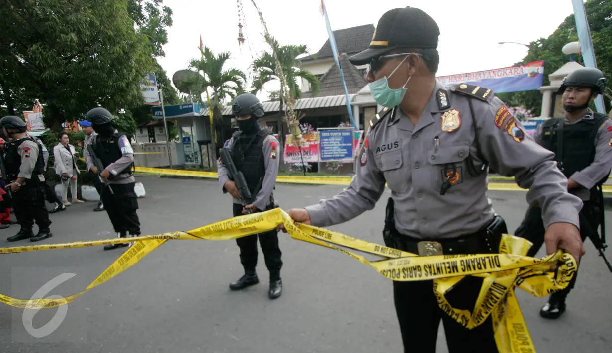 Petugas memasang garis polisi di lokasi bom bunuh diri di Mapolresta Solo, Jawa Tengah, Selasa (5/7). Garis polisi tersebut dipasang mulai dari sisi barat jalan Adi Sucipto menuju sisi timur Jalan KS Tubun. (Liputan6.com/Boy Harjanto)