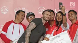 Perwakilan Atlet Asian Games Indonesia dan Menpora Imam Nahrawi swafoto bersama mantan bintang sepak bola Inggris David Beckham pada acara AIA Sepak Bola untuk Negeri di Jakarta, Minggu (25/3). (Liputan6.com/Herman Zakharia)