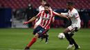 Striker Atletico Madrid, Luis Suarez, berusaha melewati pemain Sevilla, Fernando, pada laga Liga Spanyol di Stadion Wanda Metropolitano, Selasa (12/1/2021). Atletico Madrid menang dengan skor 2-0. (AFP/Pierre-Philippe Marcou)