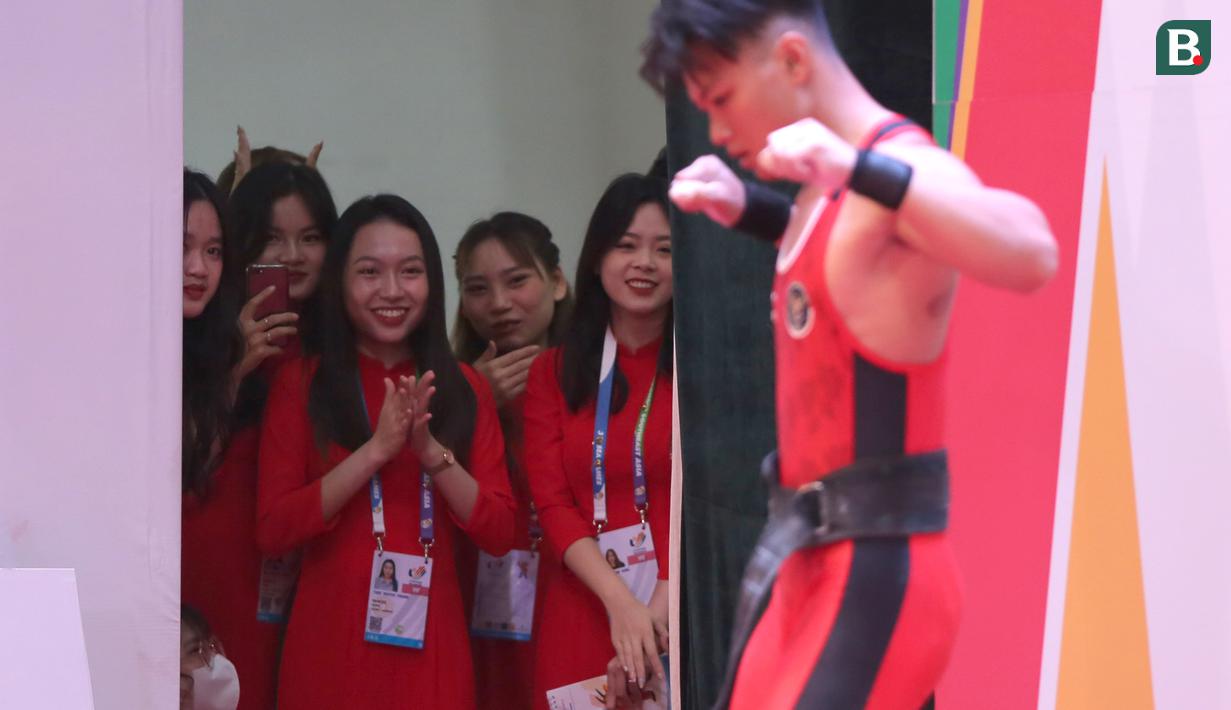 Perlombaan angkat besi di kelas 73 kg putra yang dimenangi lifter Indonesia, Rahmat Erwin Abdullah di SEA Games 2021 ternyata menjadi kelas favorit di antara kelas-kelas lainnya. Buktinya, perjuangan para lifter di kelas ini mampu menyedot perhatian para kaum hawa yang sejatinya bertugas sebagai panitia. (Bola.com/Ikhwan Yanuar)