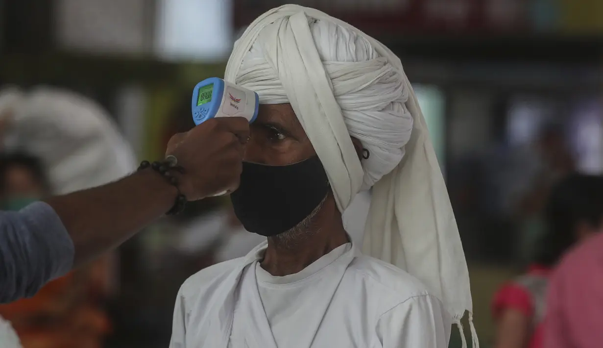 Petugas kesehatan memeriksa suhu penumpang saat melakukan skrining untuk tes COVID-19 di stasiun kereta jarak jauh di Mumbai, Maharashtra, Minggu (21/3/2021). India mencatat rekor lonjakan harian tertinggi dalam hampir empat bulan terakhir. (Ap Photo/Rafiq Maqbool)