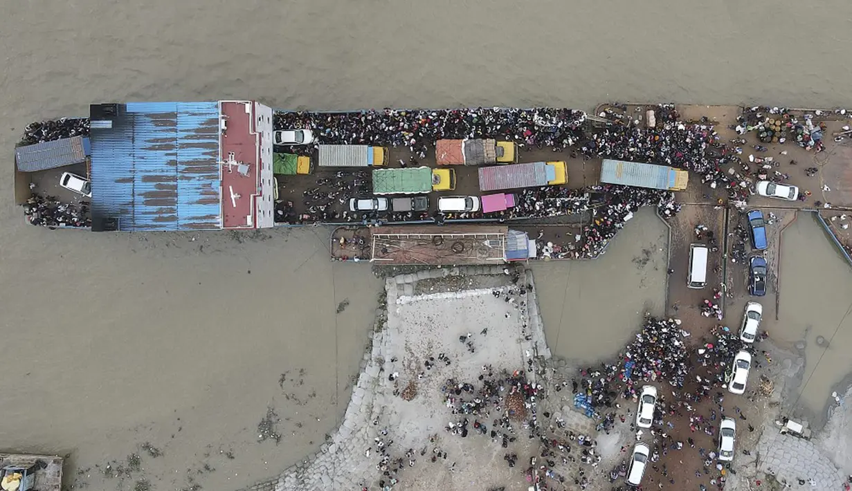 Foto udara yang diambil pada 27 Juni 2021 ini memperlihatkan penumpang naik kapal feri jelang pengetatan lockdown, Munshiganj, Bangladesh. Ribuan pekerja migran meninggalkan Ibu Kota Bangladesh, Dhaka, jelang lockdown yang diperketat. (Munir Uz zaman/AFP)