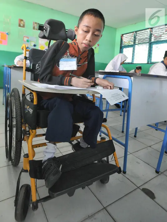 Fauzan Akmal Maulana menunggu pelaksanaan try out ujian di SMP 1 Terbuka Tangerang Selatan, Jumat (22/3). Remaja 15 tahun ini sudah sejak kecil menderita otot lemah, namun masih setiap hari semangat berangkat sekolah. (merdeka.com/Arie Basuki)