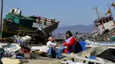 Warga duduk di samping puing-puing dari toko mereka usai gempa bumi melanda Kota Coquimbo, Chile (17/9/2015). Gempa yang menewaskan sekitar sepuluh orang dan memaksa satu juta orang mengungsi dari rumah mereka ke dekat pantai. (REUTERS/Ivan Alvarado)