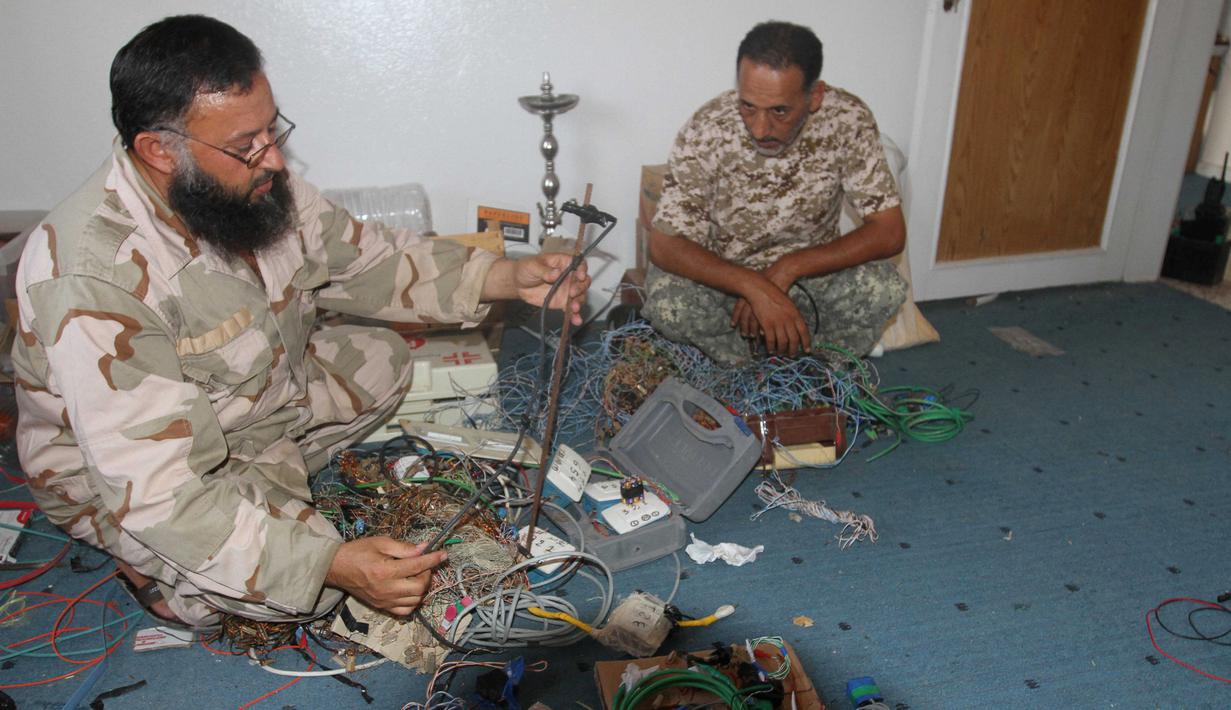 Anggota militer Libya menjinakkan bom rakitan milik militan ISIS di Sirte (5/9). Setelah berhasil menaklukkan salah satu markas ISIS, Militer Libya menemukan bom rakitan dan senjata peledak lainnya yang masih aktif. (REUTERS/Hani Amara)