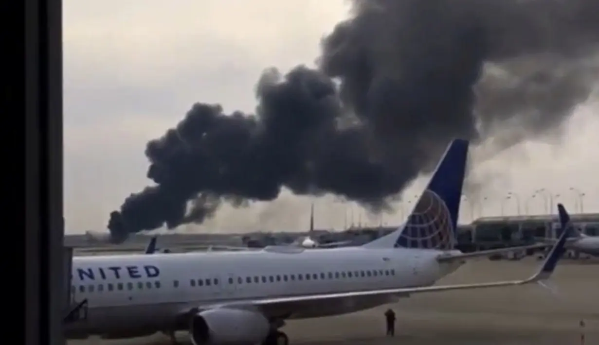Kepulan Asap terlihat dari Pesawat American Airlines yang terbakar di Bandara O'Hare Chicago, AS (28/10). Sejumlah penumpang di dalam kabin telah dievakuasi ketika asap hitam mulai mengepul dari pesawat. (Courtesy of Robocast.com/Handout via REUTERS)