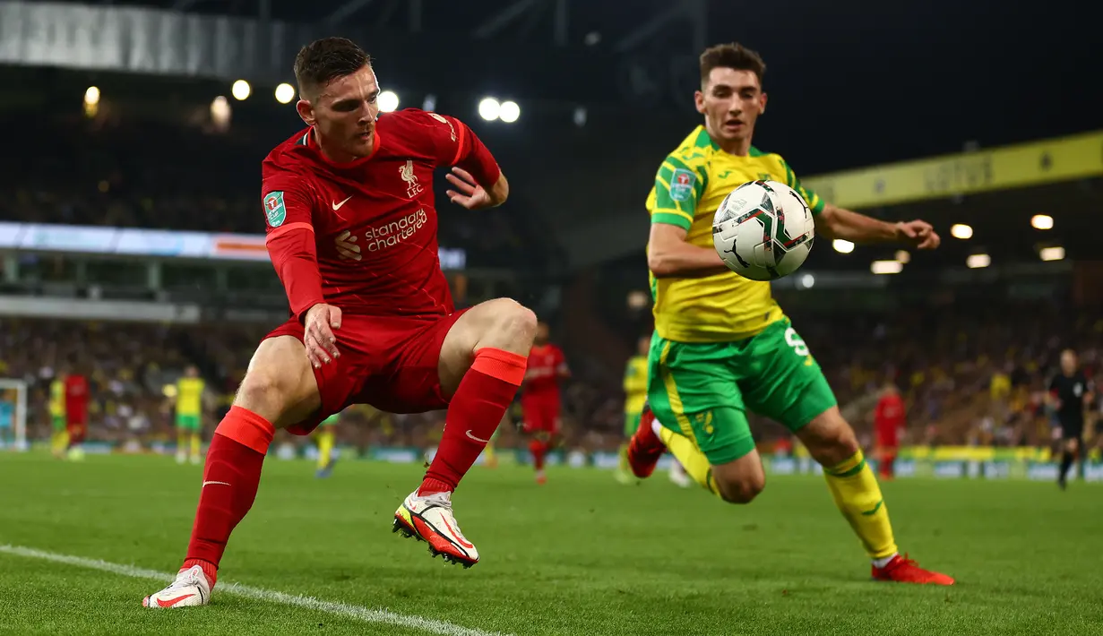 Bek Liverpool Andrew Robertson bersaing dengan gelandang Norwich City Billy Gilmour pada babak ketiga Piala Liga Inggris di Carrow Road, Rabu (22/9/2021) dinihari WIB. Liverpool sukses menghajar Norwich City tiga gol tanpa balas di kandang lawan. (ADRIAN DENNIS / AFP)