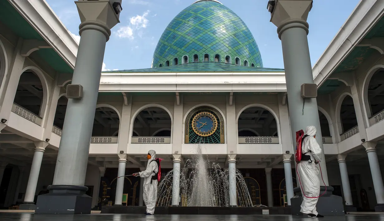 Pekerja dari otoritas penanggulangan bencana setempat menyemprotkan desinfektan di sebuah masjid di Surabaya, Jawa Timur, Selasa (17/3/2020). Kegiatan tersebut dilakukan untuk mencegah penyebaran Virus Corona COVID-19. (Photo by Juni Kriswanto / AFP)