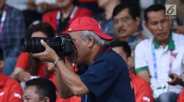 Menteri PUPR, Basuki Hadimuljono terlihat mengabadikan momen saat laga semifinal bulu tangkis beregu putra Asian Games 2018, Indonesia melawan Jepang di Jakarta, Selasa (21/8). Indonesia unggul dan lolos ke final. (Liputan6.com/Helmi Fithriansyah)