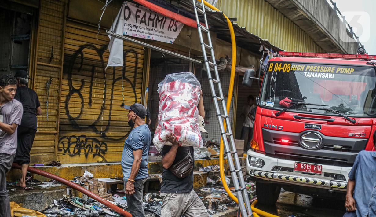 Pedagang menyelamatkan barang dagangan saat proses pendinginan oleh damkar dari kebakaran di Pasar Pagi Asemka, Jakarta, Jumat (18/11/2022). Kebakaran terjadi sekitar pukul 11.30 WIB. Sebanyak Sebanyak 14 unit kendaraan pemadam beserta 70 personel dikerahkan untuk menanggulangi kebakaran. (Liputan6.com/Faizal Fanani)